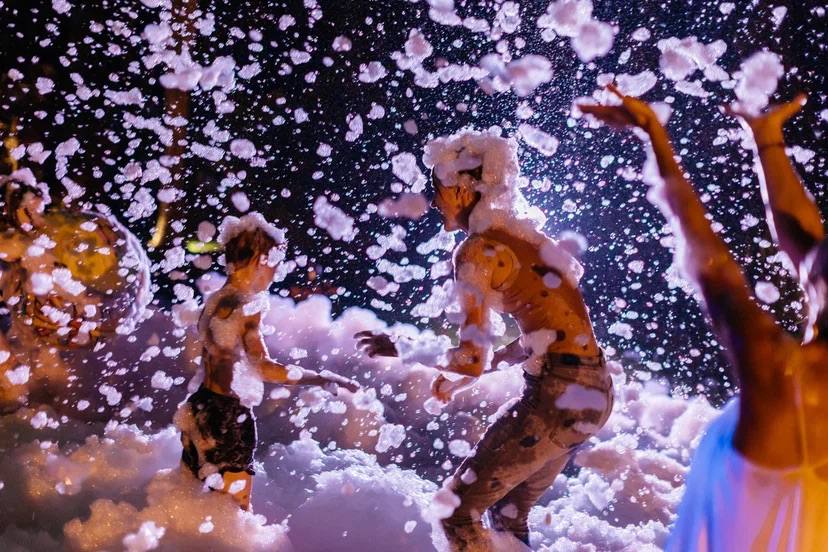 A foam party after dark, lit like a music video — photo 1