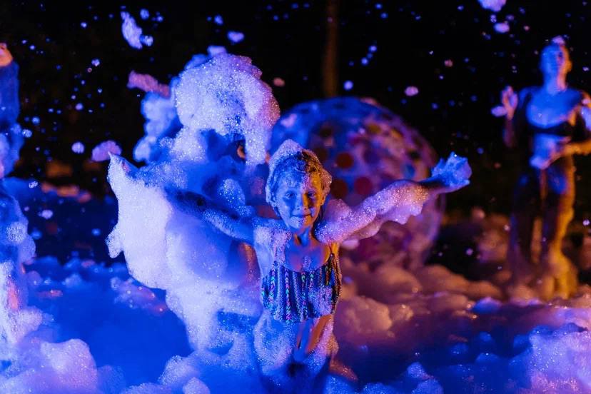 A foam party after dark, lit like a music video — photo 8
